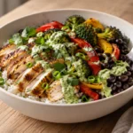 High protein chicken bowl with sliced chili-lime chicken, rice, roasted broccoli, peppers, black beans, and green sauce